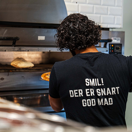 En kok der tager en pizza ind/ud af pizzaovnen fra Pops Pizza i Ishøj.